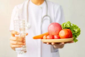 Doctora con una botella de agua y un plato con frutas y verduras