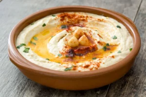 Hummus de garbanzos en un plato de barro sobre mesa de madera